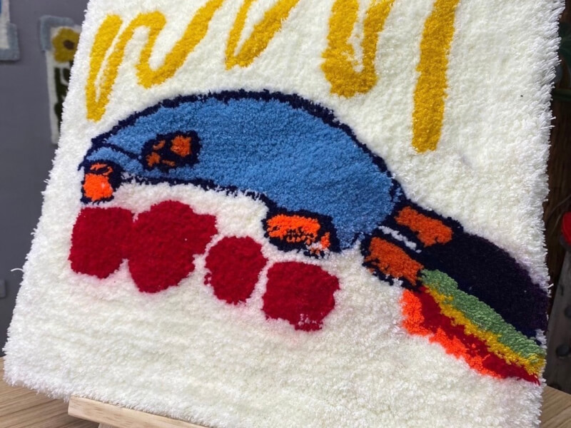 A completed hand tufted rug with an abstract design in blue, red, white and yellow